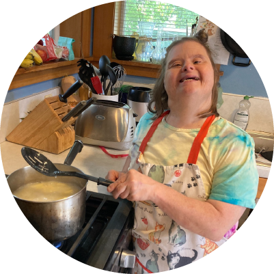 A person cooks in a kitchen and smiles.