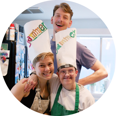 Three people pose together in a kitchen and smile