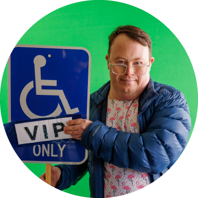 A person with down syndrome holds up a VIP parking sign