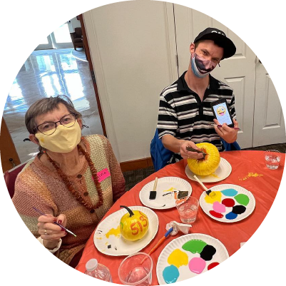 Two people sit at a table painting pumpkins