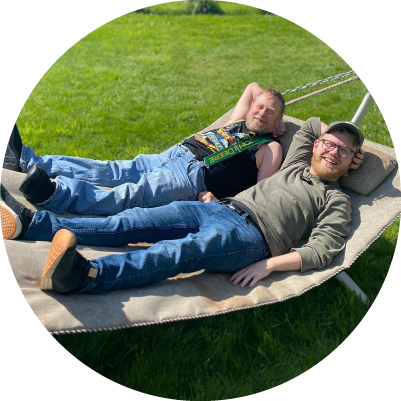 Two people lie on a hammock next to each other and laugh