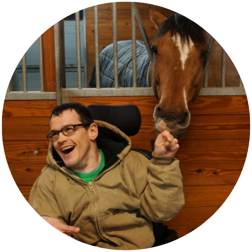 A core member laughs while petting a horse.